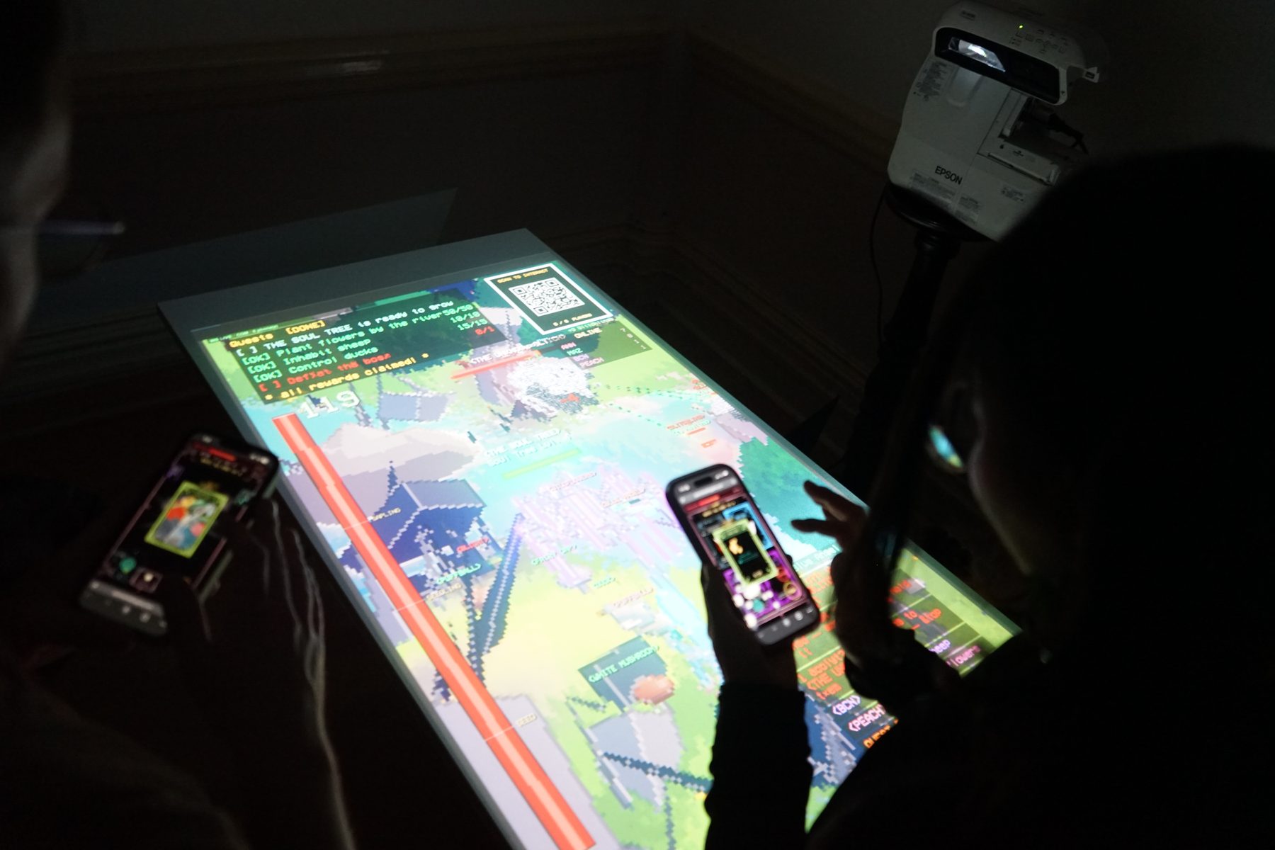 Two players holding phones over the projected table